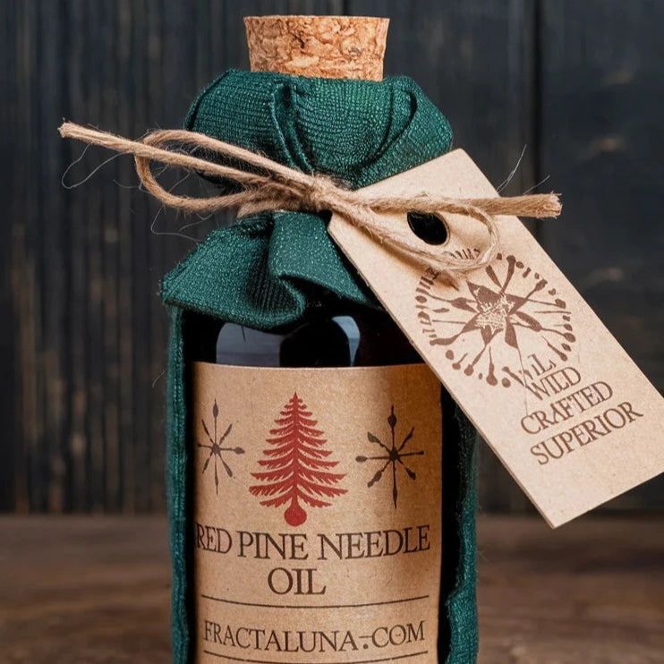 A beautifully packaged bottle of Red Pine Needle Oil wrapped in green fabric with a cork top and a tag reading 'Wild Crafted Superior,' showcasing premium quality from Fractaluna.com